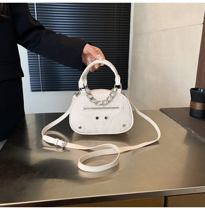Dettaglio borsa bianca goffrata coccodrillo con catena d'argento e borchie fitte