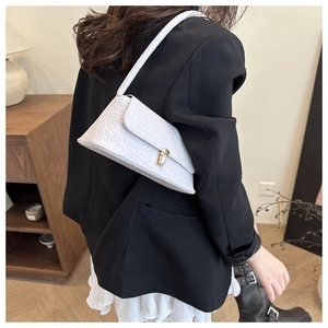 Détail d'un sac baguette blanc avec boucle dorée et texture tissée élégante