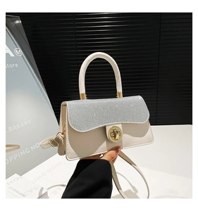 Detail of cream leather handbag with sparkling sequin cover and gold rotary lock buckle