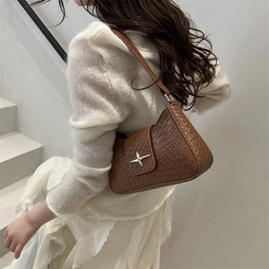 French style woven brown underarm bag with silver star buckle worn on a shoulder