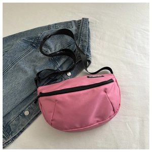 Detail of pink nylon crossbody bag with fashion label and adjustable black strap