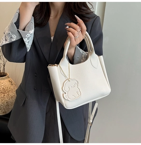 Sac seau blanc chic à texture litchi avec breloque chien porté par un mannequin