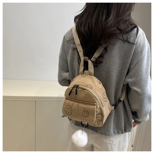 Detail of khaki corduroy mini backpack with smiley face prints and white pompom charm