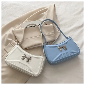 Detail of elegant bow buckle and geometric stitching on cream and light blue shoulder bags