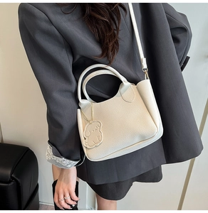 Sac seau en cuir blanc avec bijou de sac chien porté par un mannequin en veste grise