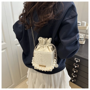 Detail of white bucket bag with snake-embossed texture and pearl bead handle