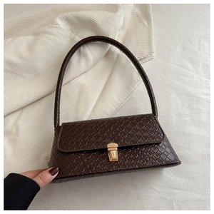Détail d'un sac à main marron foncé avec texture tissée et fermoir doré chic