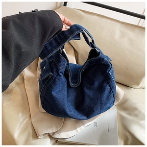 Détail du sac cabas en denim bleu foncé délavé montrant la texture et la poche latérale