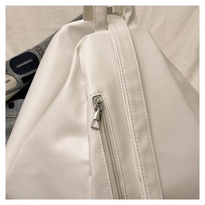 Detailed macro view of the silver metal zipper and white leather texture on the backpack