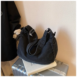 Détail du sac hobo en denim noir délavé avec boucle argentée sur fond minimaliste