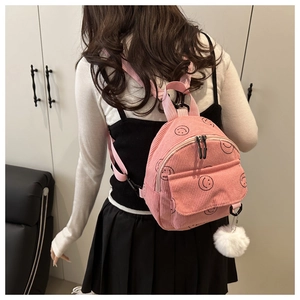 Rosa Cord-Minirucksack mit Smiley-Drucken und Plüschanhänger an einem Modell gezeigt