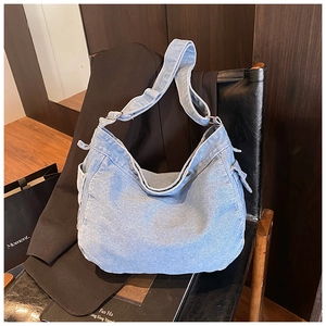 Détail du sac hobo en jean avec poche latérale et bandoulière réglable sur cuir noir