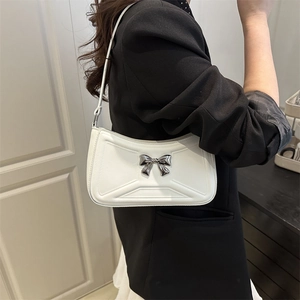 White baguette underarm bag with silver bow accent and minimalist leather texture