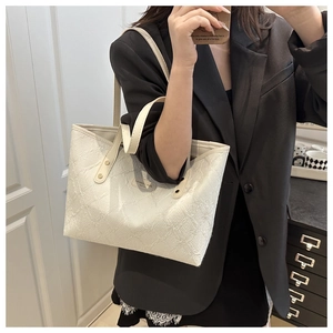 Close-up of white tote bag featuring 3D floral embossed texture and slim leather strap