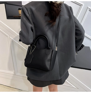 Détail du sac seau noir en cuir grainé avec un charmant pendentif en forme de petit chien