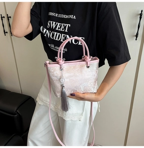 Detailed close-up of pink jacquard bucket bag with floral embroidery and tassel charm
