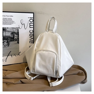 Detailed close-up of white geometric PU leather backpack on a brown fabric background
