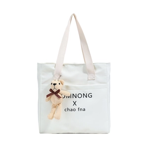 Minimalist white tote bag with wide cream handles and a cute bear plush keychain charm