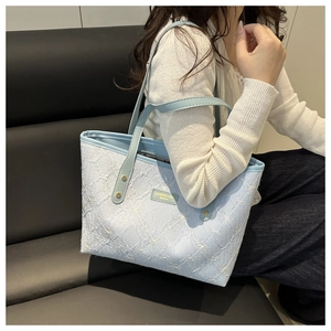 Detail of light blue tote bag with floral embroidery, quilting and leather handles
