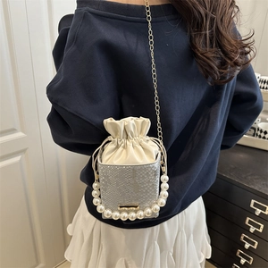 Chic silver faux snake bucket bag with large pearl handle and gold chain strap worn by model
