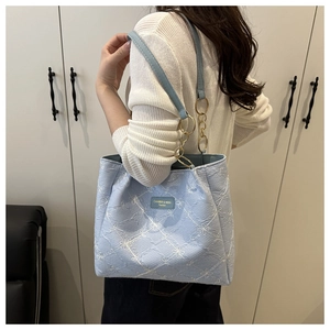 Detail of light blue tote bag featuring 3D floral embroidery and golden chain strap