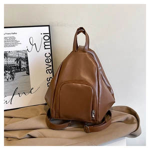Detailed view of brown faux leather backpack with triangular shape and front zipper pocket
