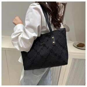 Detail of black tote bag featuring textured diamond quilting and subtle glitter finish