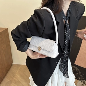 Sac baguette blanc à motif crocodile avec boucle dorée porté par un modèle