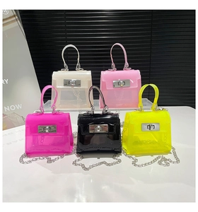 Mini jelly bags in vibrant colors with top handles and chain straps displayed on a stand