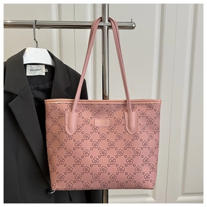 Close-up of pink cherry blossom tote bag with golden logo plaque on white door background