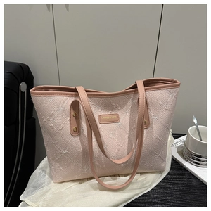 Detail shot of a light pink tote bag with white butterfly embroidery on a textured fabric