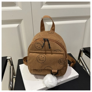 Detail eines braunen Cord-Minirucksacks mit schwarzem Smiley und weißem Bommel