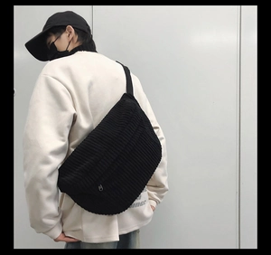 Male model wearing large black corduroy crescent crossbody bag with adjustable strap