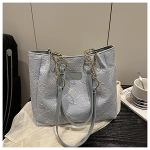 Detail of light blue nylon tote bag with floral embroidery and gold chain strap texture