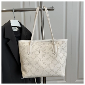 Detail of off-white tote bag featuring floral embossing and metallic logo plate