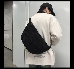Detail of black corduroy crossbody bag showing adjustable strap and large capacity on model