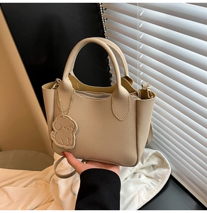 Détail du sac cabas beige en cuir grainé avec pendentif chien et bandoulière amovible