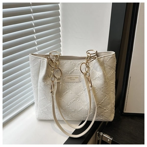 Detailed macro view of the embossed white tote bag texture with elegant chain strap