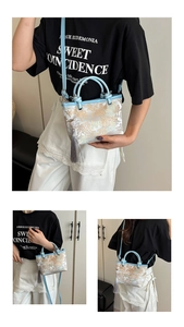 Close-up of floral brocade bucket bag featuring light blue trim and grey tassel detail