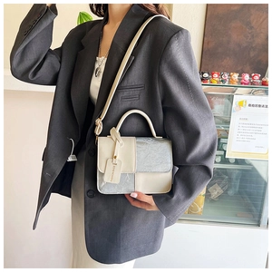 Detail of two-tone crossbody bag with cream and silver textured panels and shoulder strap