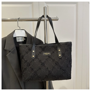 Detail of black quilted tote bag with metallic sequins and CAHRES & HEKA brand plaque