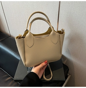 Détail du sac seau beige à motif litchi avec fermeture éclair argentée et poignées