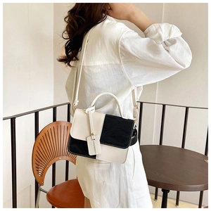 Detail of contrast black and white shoulder bag with decorative fashion brand tag