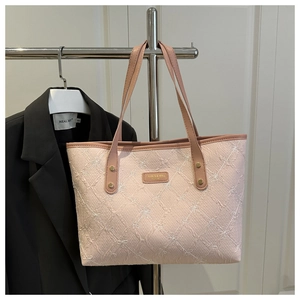 Detail of pink quilted tote bag with floral embroidery and brand metal plaque