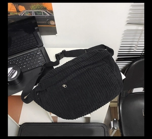 Detailed view of black corduroy crossbody bag with adjustable buckle and front zip pocket