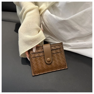 Detailed view of a brown woven leather card holder with snap closure and multi-card slots