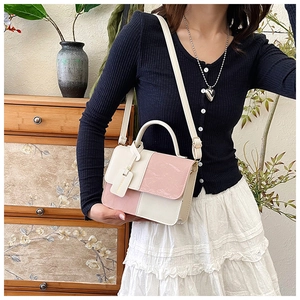 Detail shot of a pink and cream patchwork PU leather crossbody bag on a model