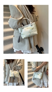 Detail of light green silk bucket bag featuring traditional bird embroidery and elegant tassel