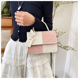 Detail of pink and beige patchwork crossbody bag with top handle and fashion tag