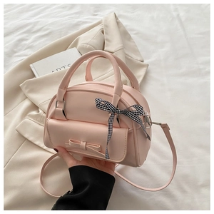 Close-up of pink PU leather shell bag with bow detail and plaid ribbon on handle